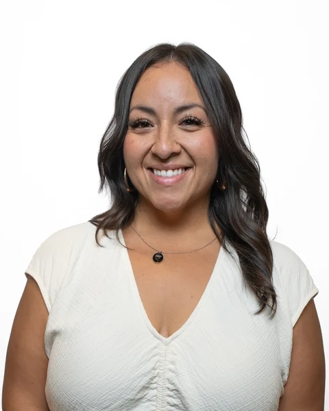 Professional headshot at the Clark Insurance office opening, Magnolia, TX: woman with dark wavy hair in a cream blouse