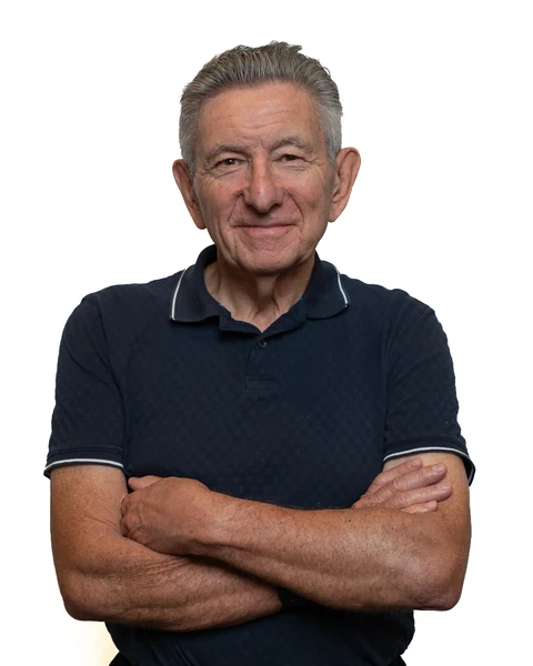 Professional headshot at the Clark Insurance office opening, Magnolia, TX: man with gray hair in a navy polo, arms crossed