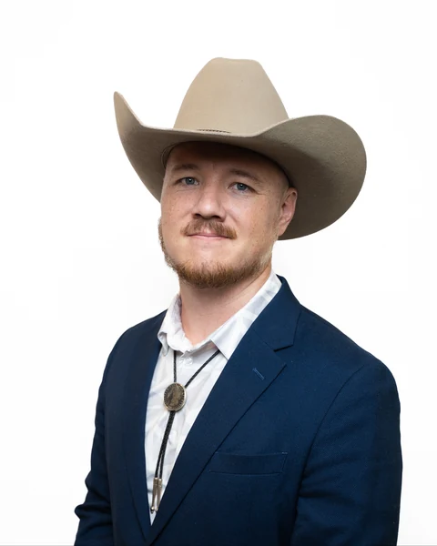 Professional headshot at the Clark Insurance office opening, Magnolia, TX: man in a cowboy hat, navy blazer and bolo tie