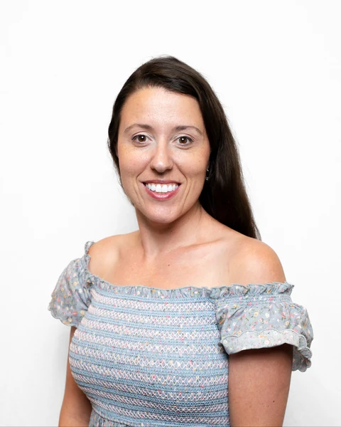 Professional headshot at the Clark Insurance office opening, Magnolia, TX: woman with long brown hair in a blue floral top